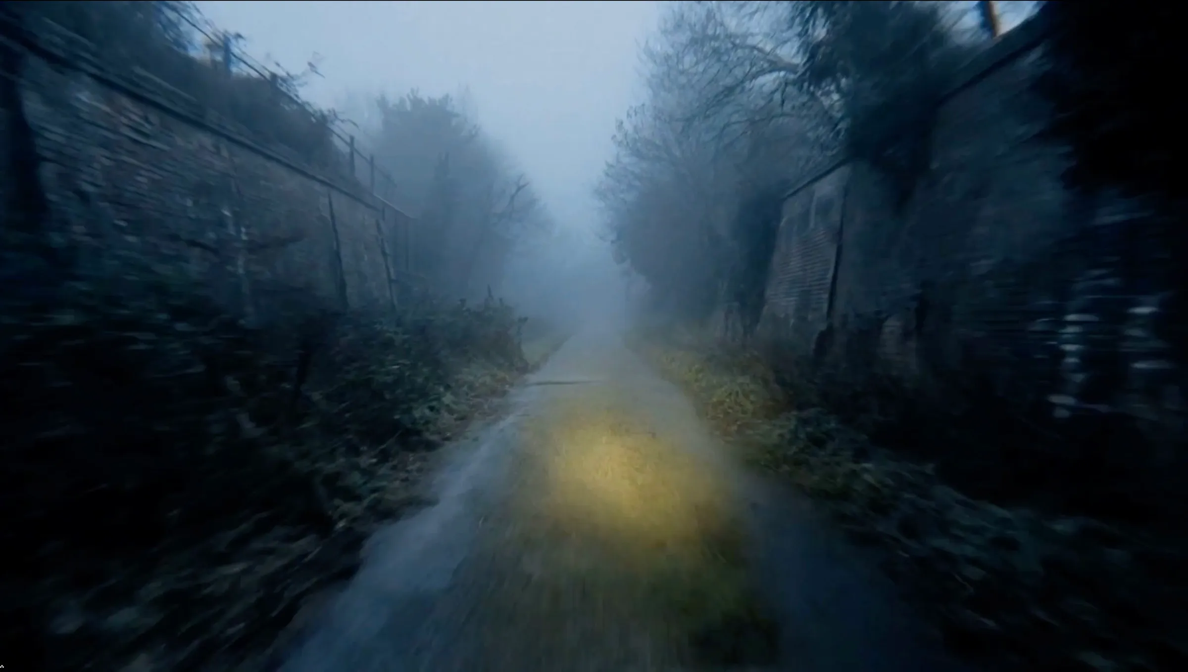 A foggy, unlit footpath running between high walls before dawn, lit only by a bicycle lamp.